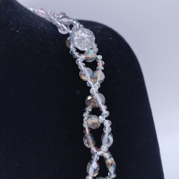 Silver bracelet with a diamond on a black stand against a light gray background