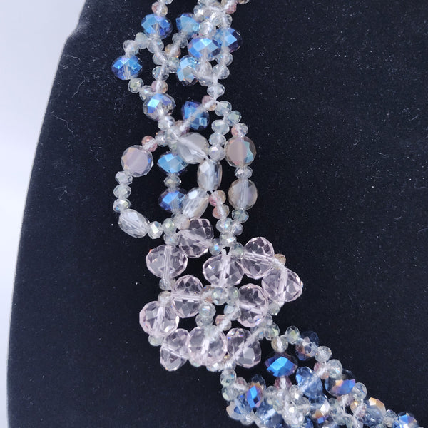 Beaded necklace with blue and clear beads on a black stand