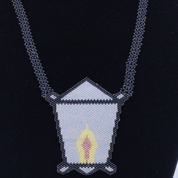 Jewelry set with necklace and earrings featuring lantern designs on a black stand.