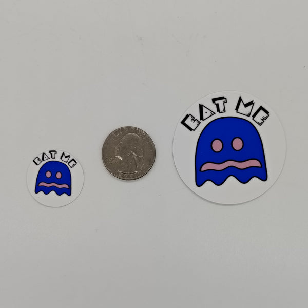 Image of 2 stickers featuring a vulnerable pacman ghost and the words eat me compared to a quarlter