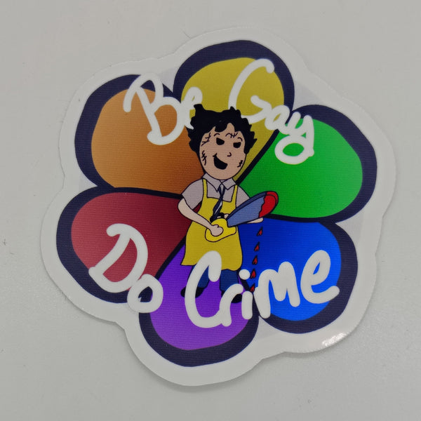 an image of a chibi version of leatherface over a background of a rainbow flower with the words be gay do crime