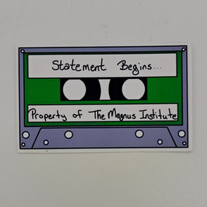 A sticker of a cassette tape with the words 'statement begins' and 'property of the magnus archives.'